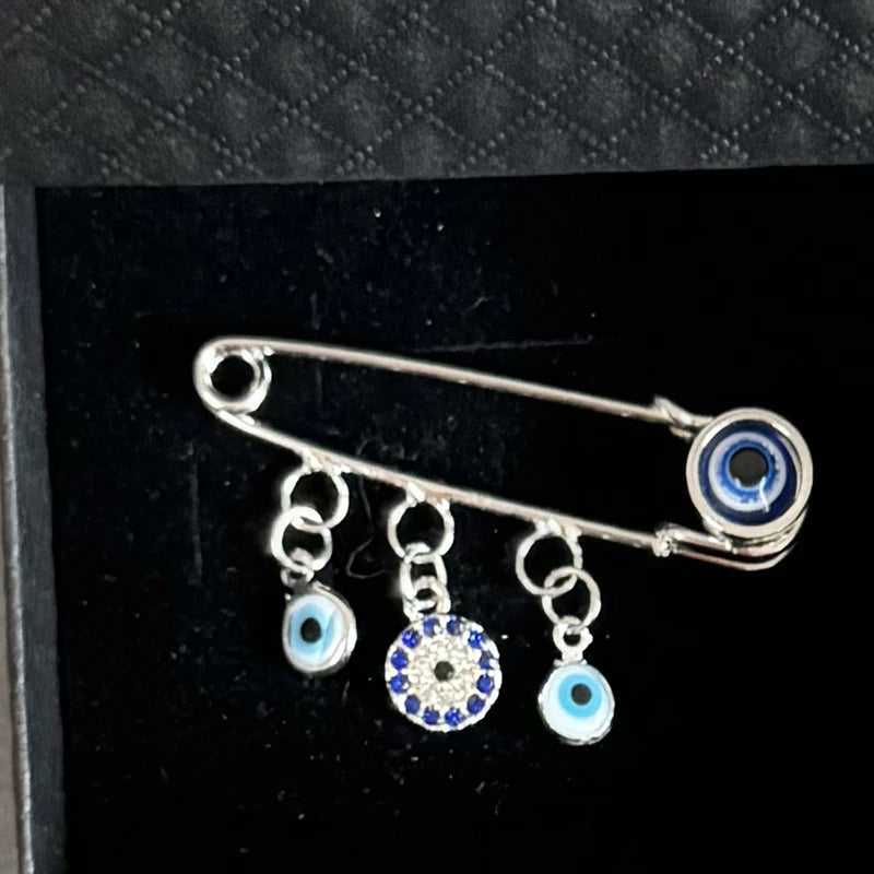 Elegant gold and silver evil eye brooch pin featuring multiple blue and white eye charms