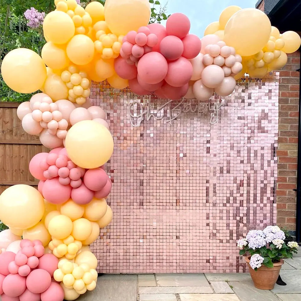 A vibrant pink and yellow balloon arch backdrop featuring shimmering sequins for a party decoration.