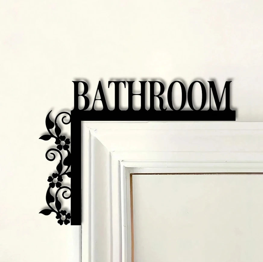 Black metal wall plaque with the word BATHROOM and a floral design on a white frame.