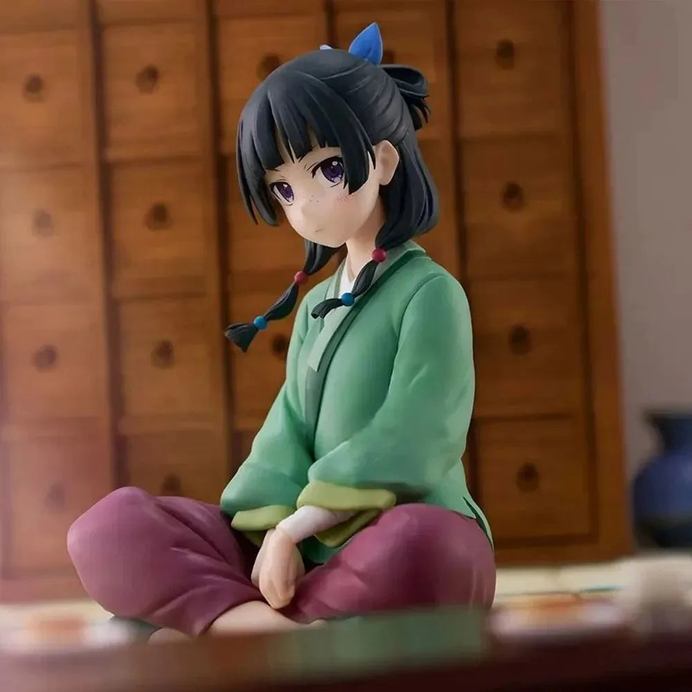 A collectible PVC figure of Maomao from The Apothecary Diaries with dark hair and a green outfit sitting in a traditional sty