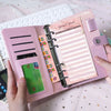 A pink leather budget sheet binder with a clip and cash envelope inside