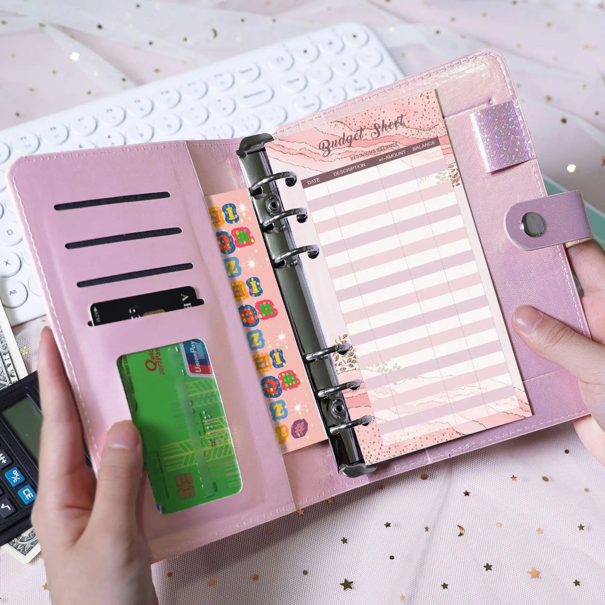 A pink leather budget sheet binder with a clip and cash envelope inside