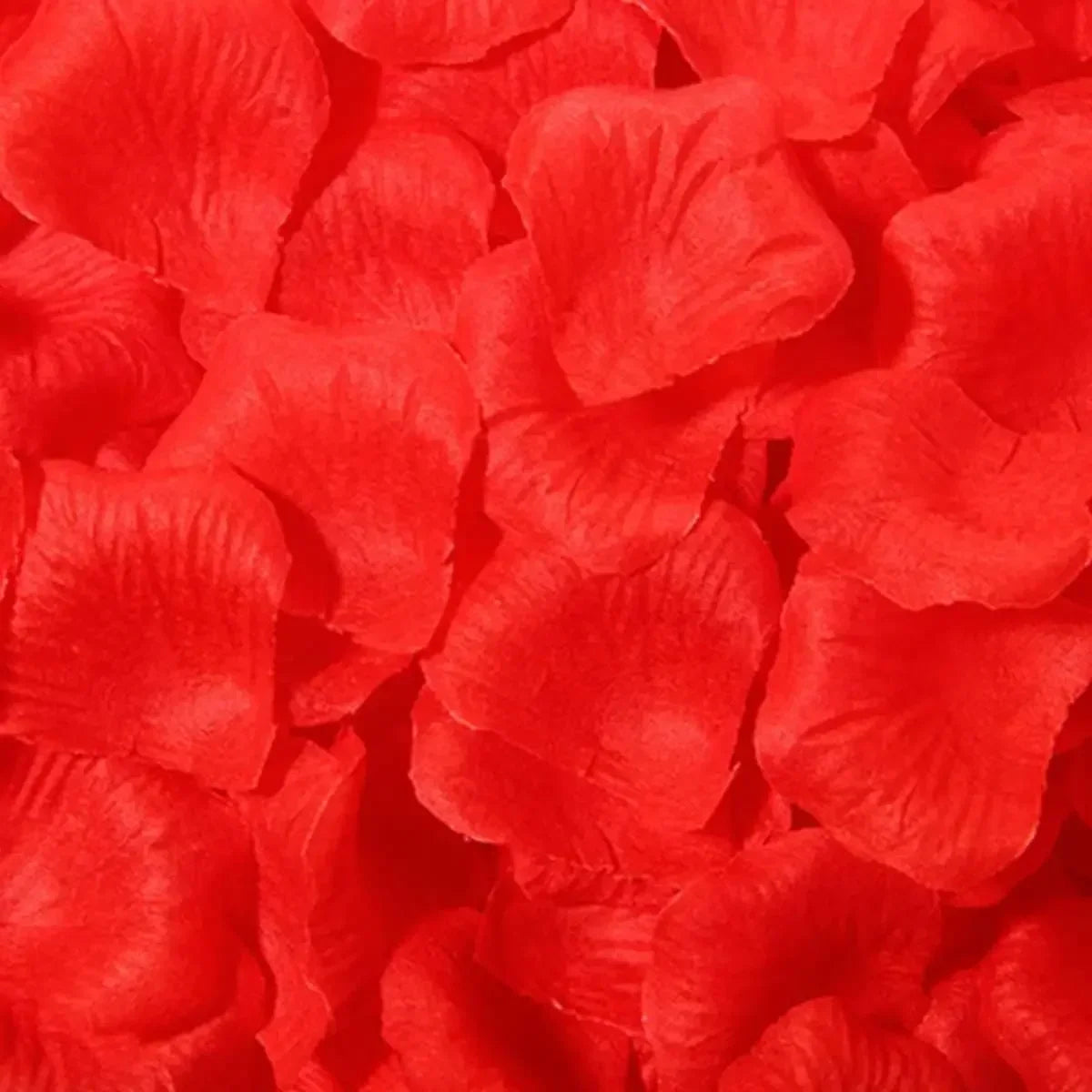A close-up of bright red silk rose petals scattered together.