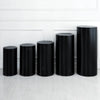 Five black spandex cylinder stands lined up against a white wall.