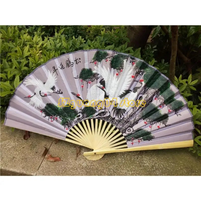A large decorative Chinese theme wall fan with purple and green stripes featuring white cranes and foliage.