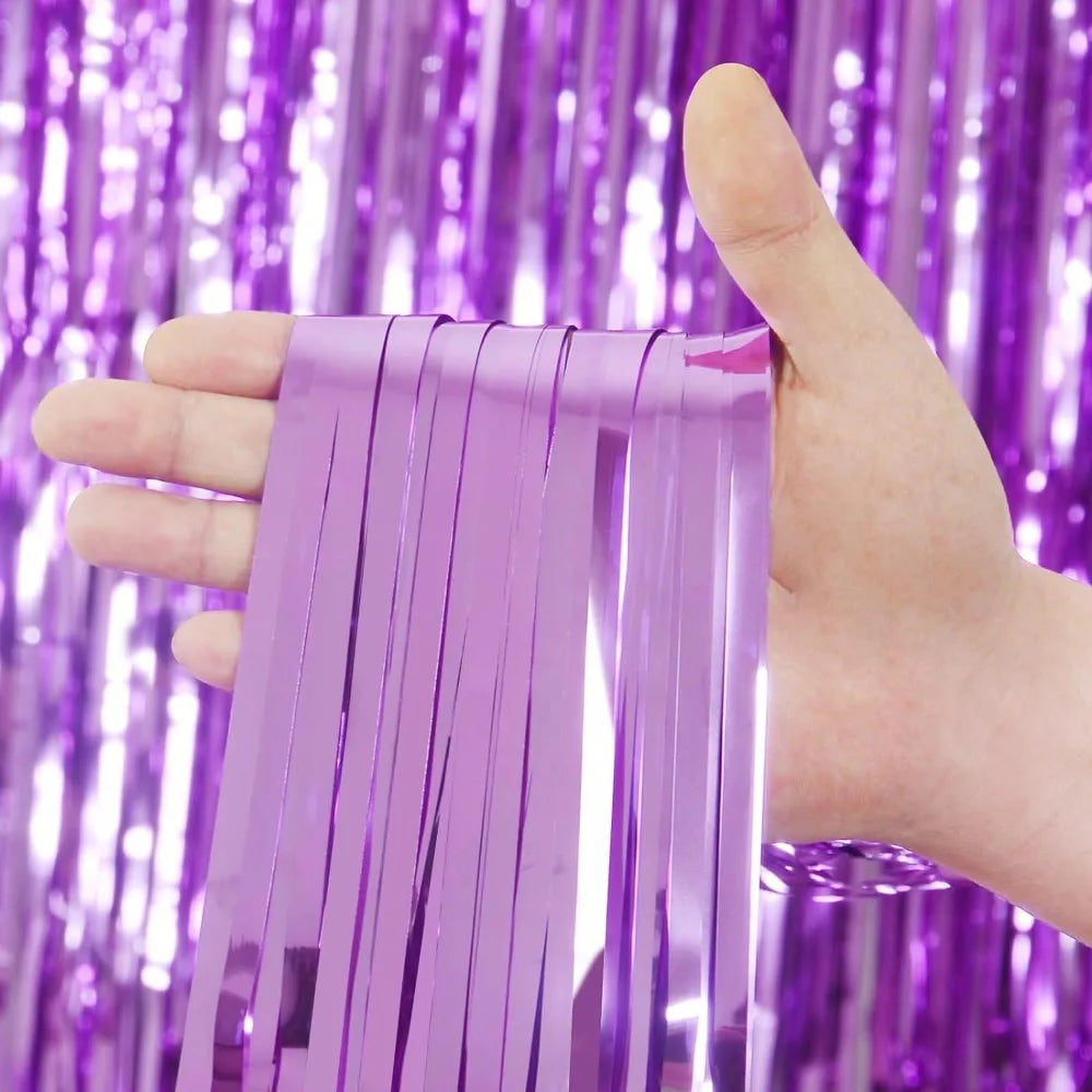 Une main tient des rideaux à franges iridescentes violettes devant un fond pailleté violet.