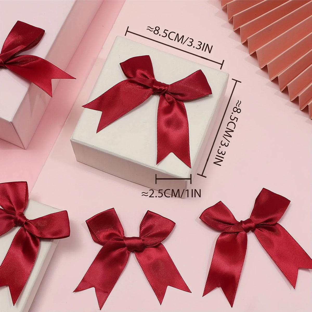 A display of elegant red satin ribbon bows for gift wrapping and decor, shown on a pink background.