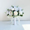 A white silk rose bridal bouquet featuring numerous white roses and greenery tied with a sheer ribbon.