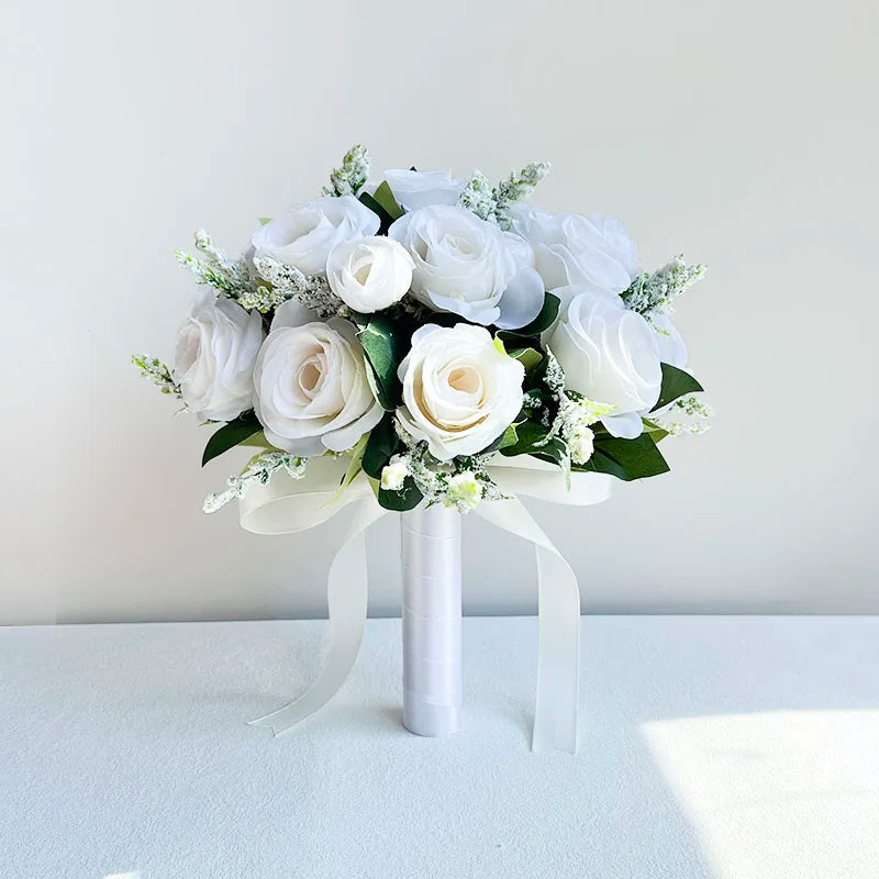 A white silk rose bridal bouquet featuring numerous white roses and greenery tied with a sheer ribbon.