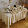 A beige cotton rectangle tablecloth set for dining or events, decorated with dried grasses and candles.
