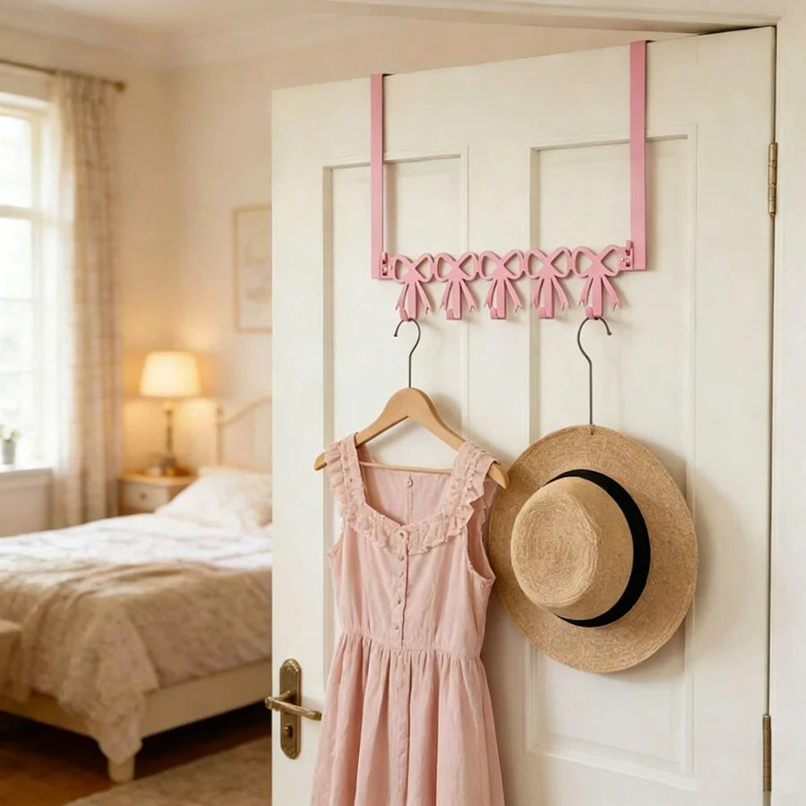 Pink heart over-the-door hook rack with five pink fabric hooks displayed on a white door.