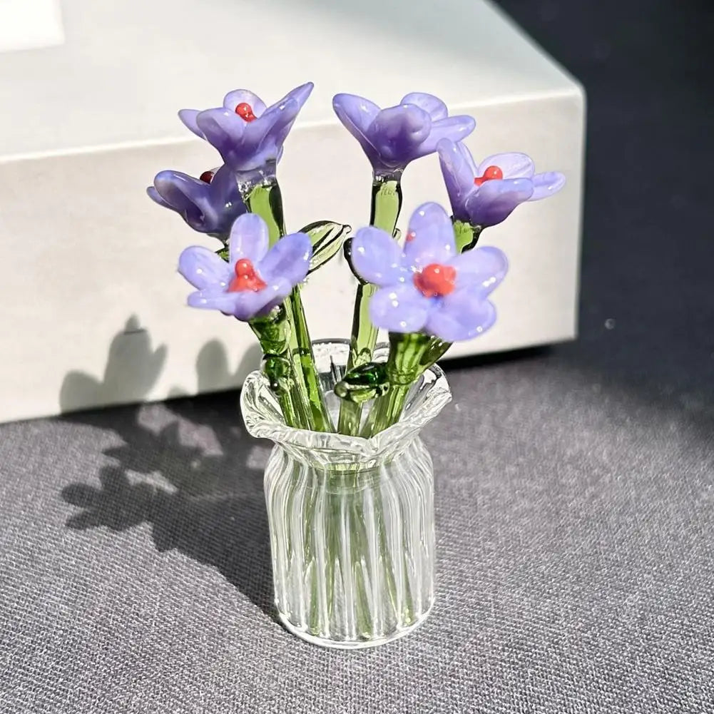 A bouquet of hand-blown glass purple flowers with red centers in a clear glass vase.