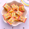 A pile of yellow and pink sweet-themed candy resin cabochons for crafting projects on a light ceramic dish.