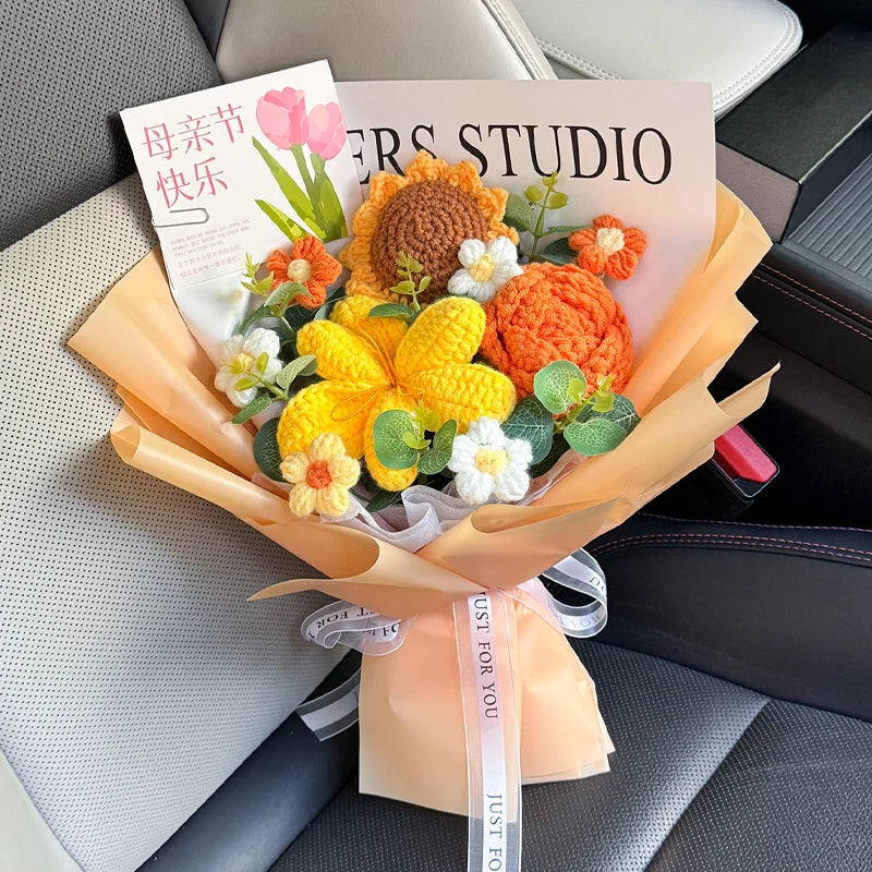 A bouquet of handmade crochet flowers in shades of orange, yellow, and white, wrapped in natural paper, resting on a car seat