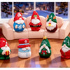 A set of festive resin Christmas dwarf figurines in red and green, including bearded men and elves, displayed on a wooden flo