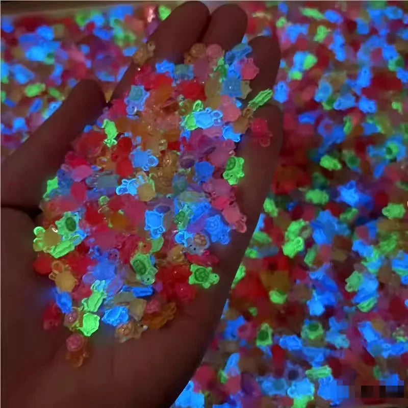 Una mano sostiene una pila de 50 adornos de uñas en forma de tortuga mini coloridos que brillan con varios colores brillantes