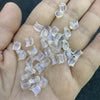 A hand holds a pack of clear, translucent cat head glass beads for jewelry making.