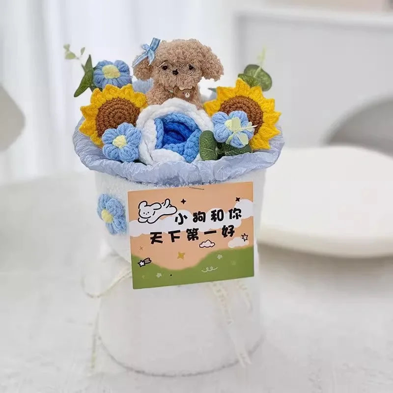A handmade crochet flower bouquet featuring a brown bear and blue and yellow flowers displayed in a white vase.