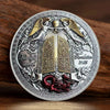 A commemorative coin featuring Saint Michael the Archangel with wings and a sword, set against a decorative border.