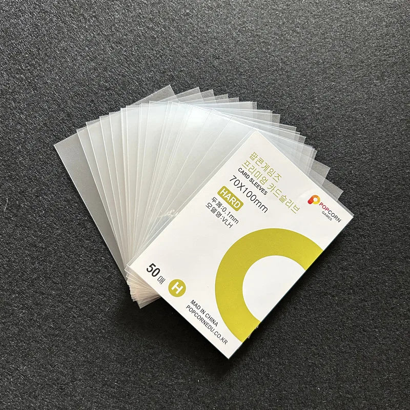 A stack of clear protective card sleeves is shown on a dark surface.