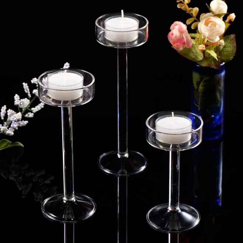 Elegant tall glass candle holder with white candles and pink roses in a dark setting