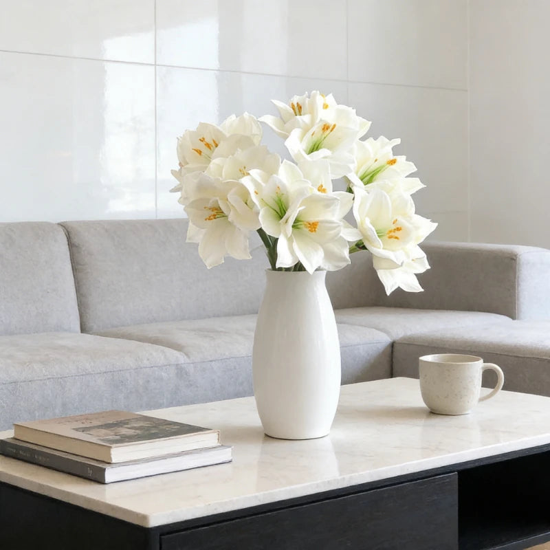 A vase of white artificial clivia amaryllis flowers on a light marble table in a modern living room