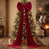 A festive Christmas tree decorated with red velvet bows and long streamers in a rustic indoor setting.
