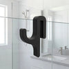 A black, modern Y-shaped shower door towel hook mounted on a glass panel in a bathroom setting.