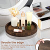 A round wooden serving tray with various glass and cosmetic bottles is displayed on a white surface.
