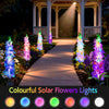 A row of colorful solar flowers lights illuminating a pathway between pillars in a garden setting.