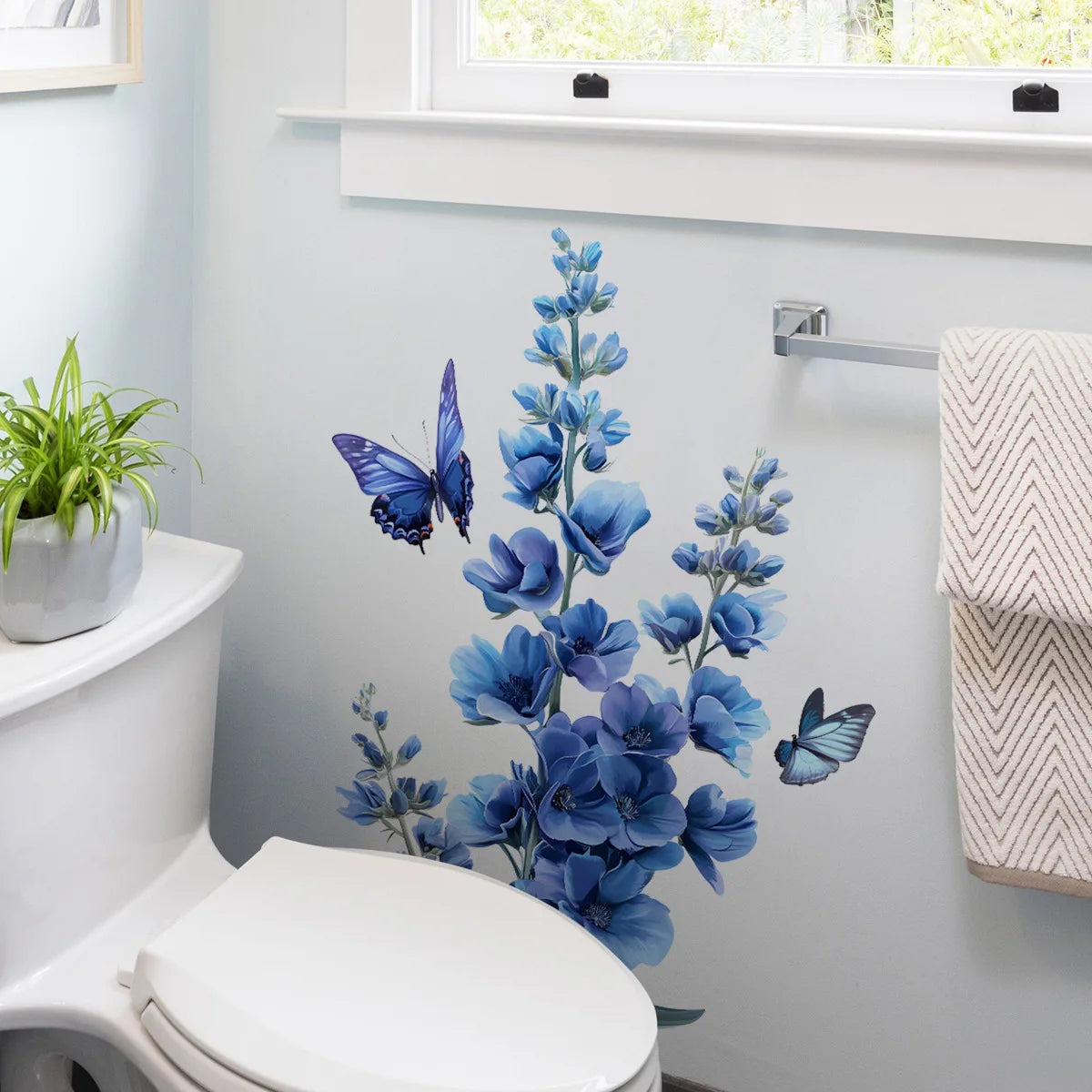 A romantic blue flower and butterfly self-adhesive wall decal displayed next to a white toilet.