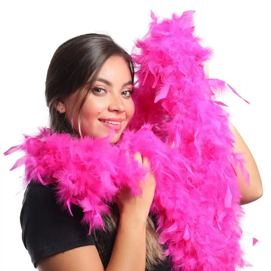 A woman holds a bright pink natural turkey feather boa for costumes and crafts.