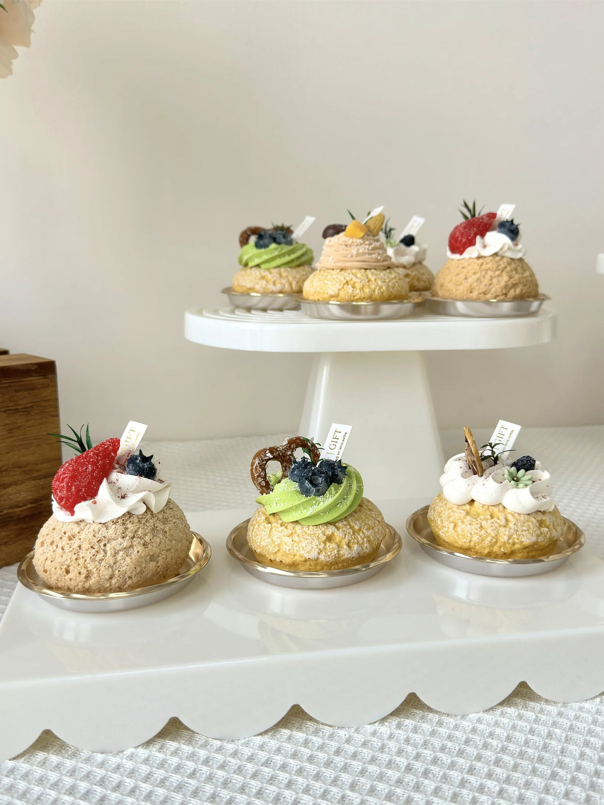 A display of six miniature cupcakes with various toppings arranged on white stands.