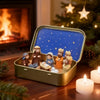 A gold box set containing a mini nativity scene with figures and a baby, set on a wooden surface near a fireplace.