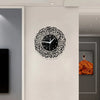 A black acrylic wall clock featuring intricate Arabic calligraphy design on a white background.
