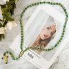A green crystal rosary necklace featuring a Saint Jude and Virgin Mary cross pendant displayed on a white background.