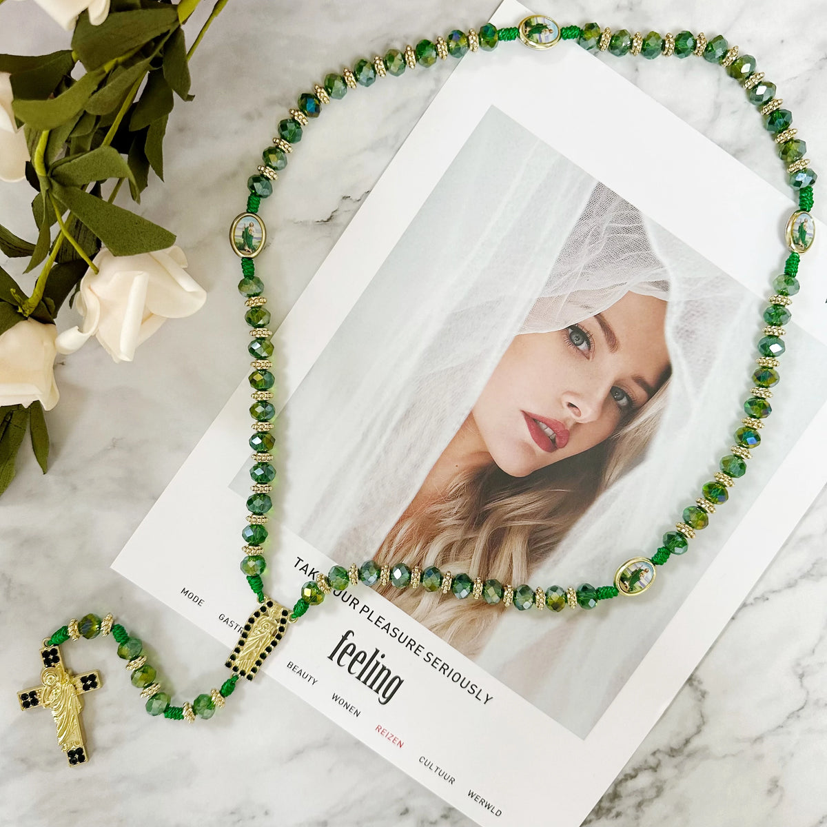 A green crystal rosary necklace featuring a Saint Jude and Virgin Mary cross pendant displayed on a white background.