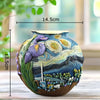 A ceramic vase painted with a starry night design featuring swirling blues, yellows, and purples on a wooden surface.