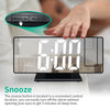 يد تضغط على زر عرض ضوء الغفوة (Snooze-Light) على ساعة منبه تعرض الساعة السادسة صباحاً.