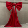 A large, vibrant red satin bow with long tulle drapes, used for event decoration.