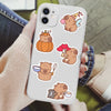 A smartphone displaying various cute capybara and pumpkin decals for crafts on a light-colored background.