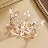 A delicate gold crown featuring pearl accents, displayed inside a light brown box.