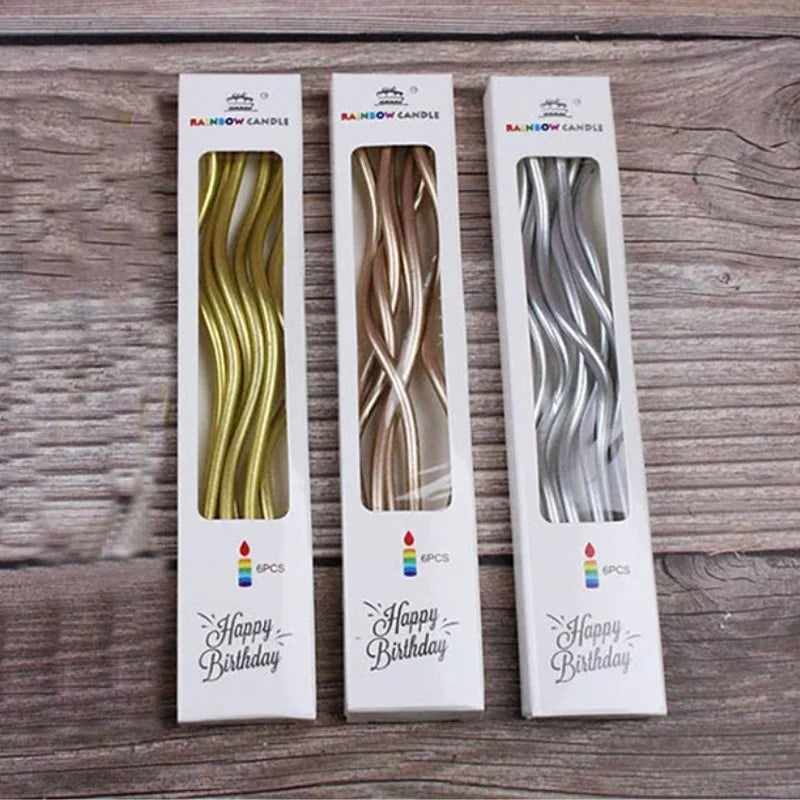 Three glass candles with curved decorative designs in gold, bronze, and silver for a birthday gift set