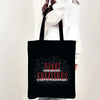 A black tote bag with a festive Christmas design featuring sparkling text that reads Merry Christmas.