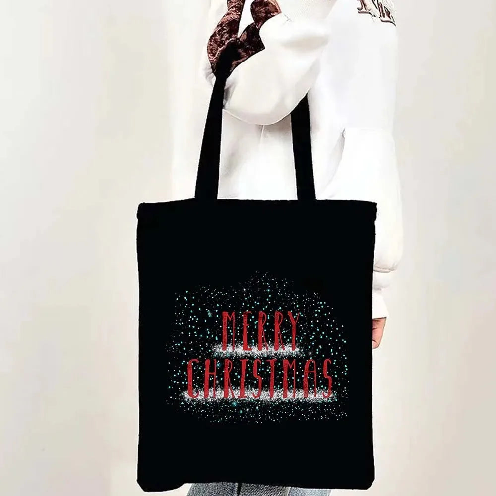 A black tote bag with a festive Christmas design featuring sparkling text that reads Merry Christmas.