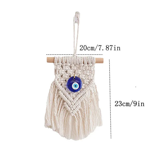 Macrame wall hanging featuring a white fringe and a blue evil eye pendant, suspended by a cord.