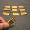 A set of ten small, rectangular gold-colored fortune charms arranged in a row on a dark surface.