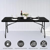 A black stretch spandex tablecloth set displayed on a table with dinnerware and a bottle of wine.