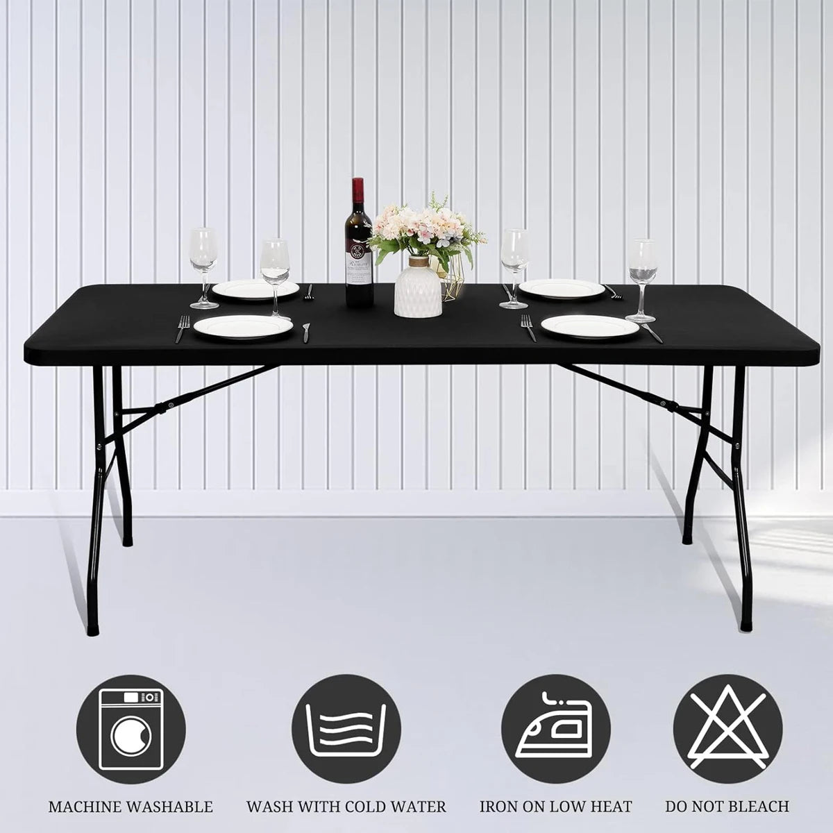 A black stretch spandex tablecloth set displayed on a table with dinnerware and a bottle of wine.