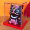 A solar-powered waving lucky cat figurine with black and pink features displayed in a clear box on a red stand.